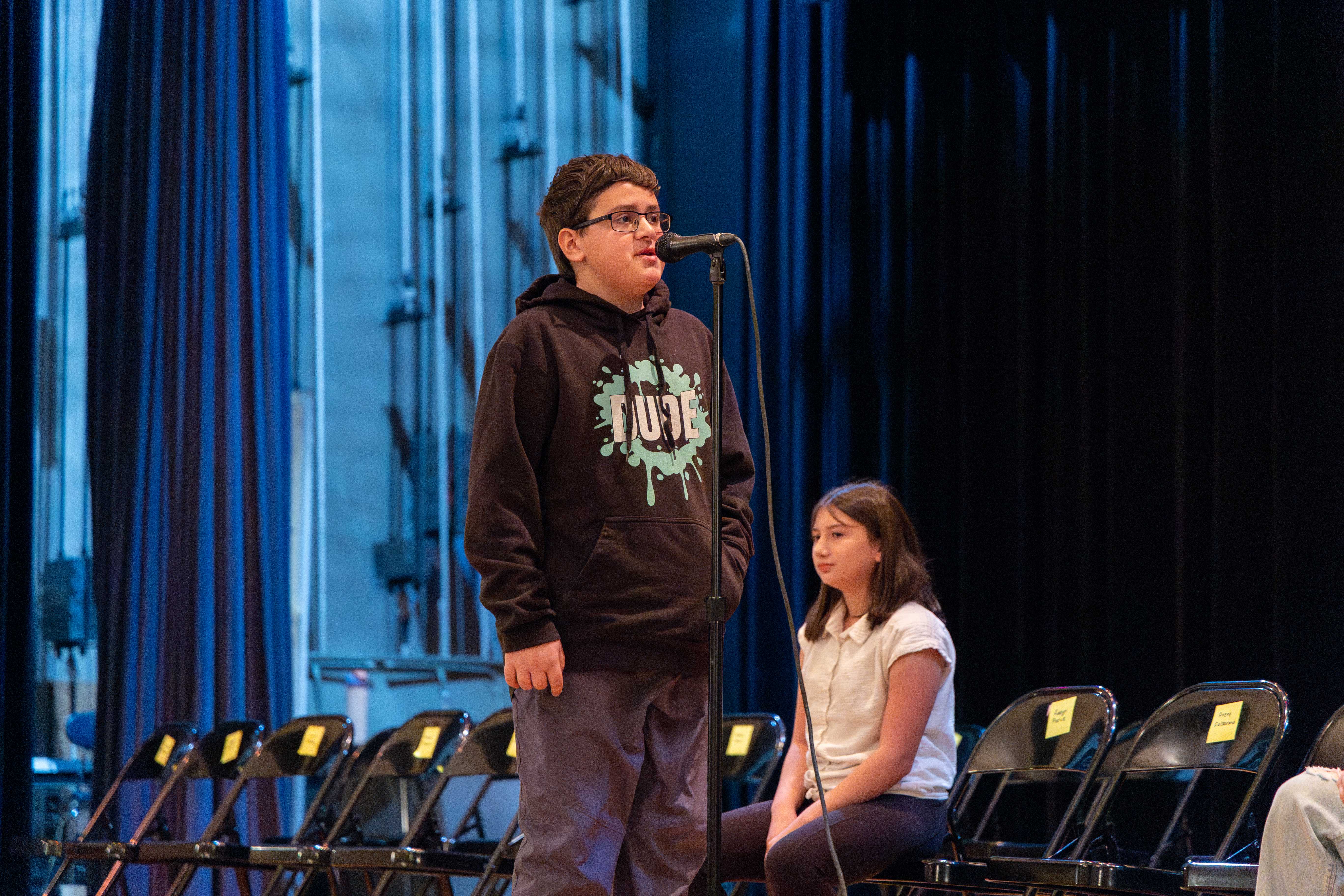 A student spells at word at the microphone